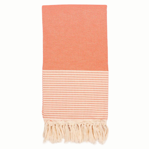 A cotton towel in an orange color with a subtle striped pattern and white fringe.